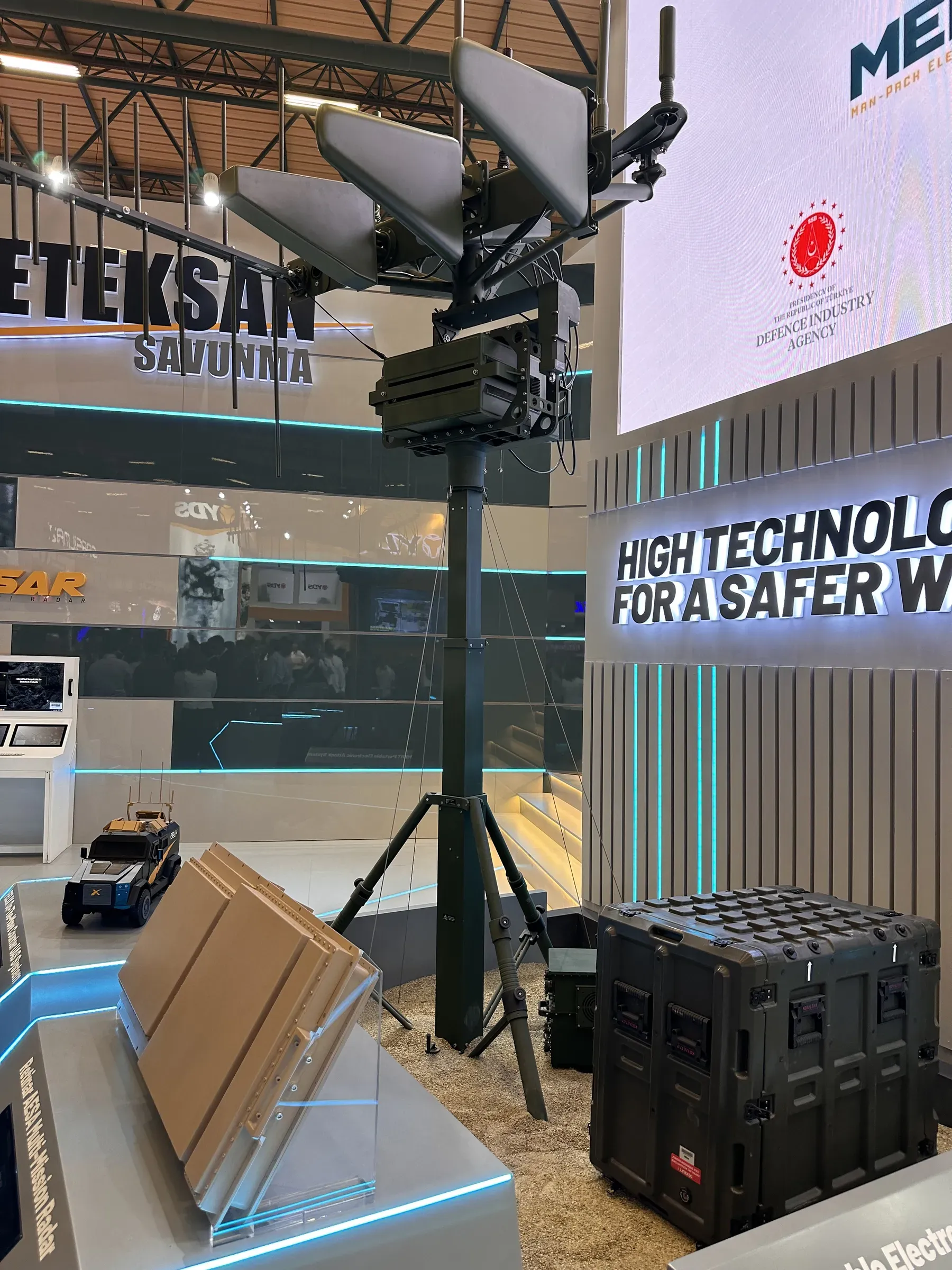 Meteksan'ın kapalı alandaki standında anten yükünü taşıyan tripod üzerindeki mast; yanında sağlamlaştırılmış rack sandıkları