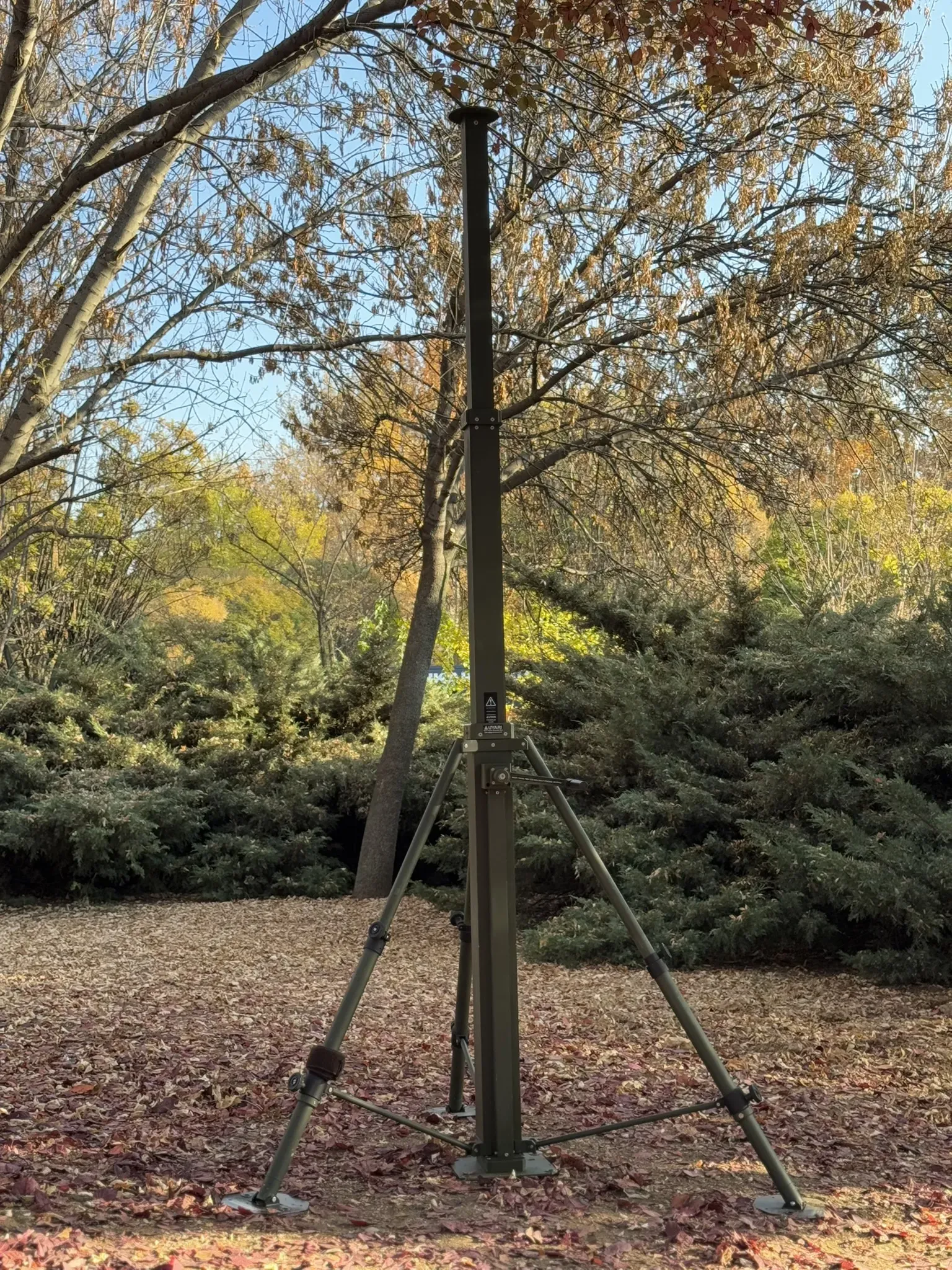Sonbahar ormanında tripod üzerinde tam açılmış manuel mast, çıplak ağaçların arasından yerden görünüm