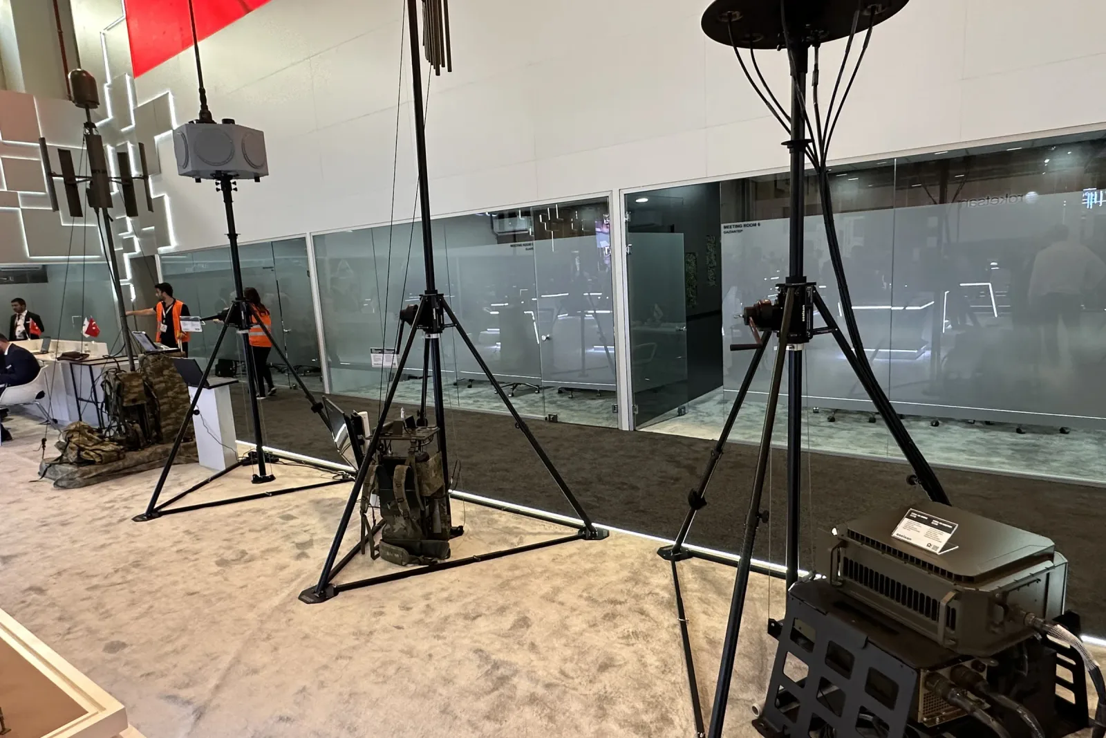 Fuar zemininde kurulmuş portatif tripod-mast; gergi halkaları ve faydalı yük başı görünüyor