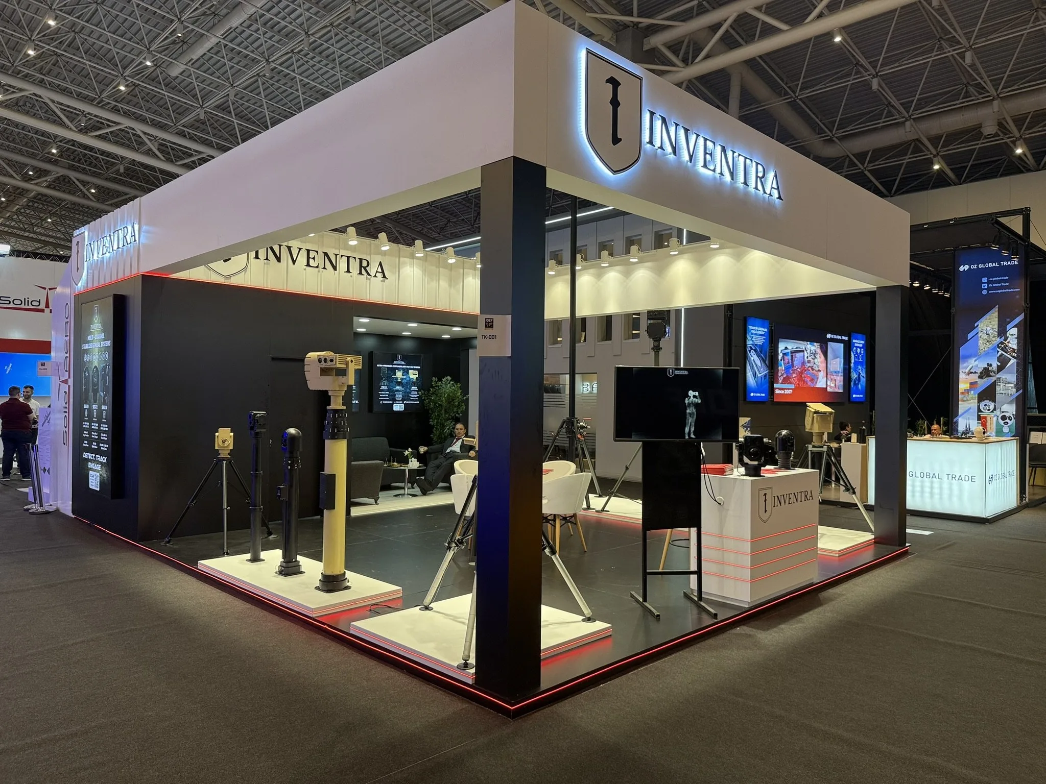 Standın geniş görünümü; platformda mastlar, ekran ve banko