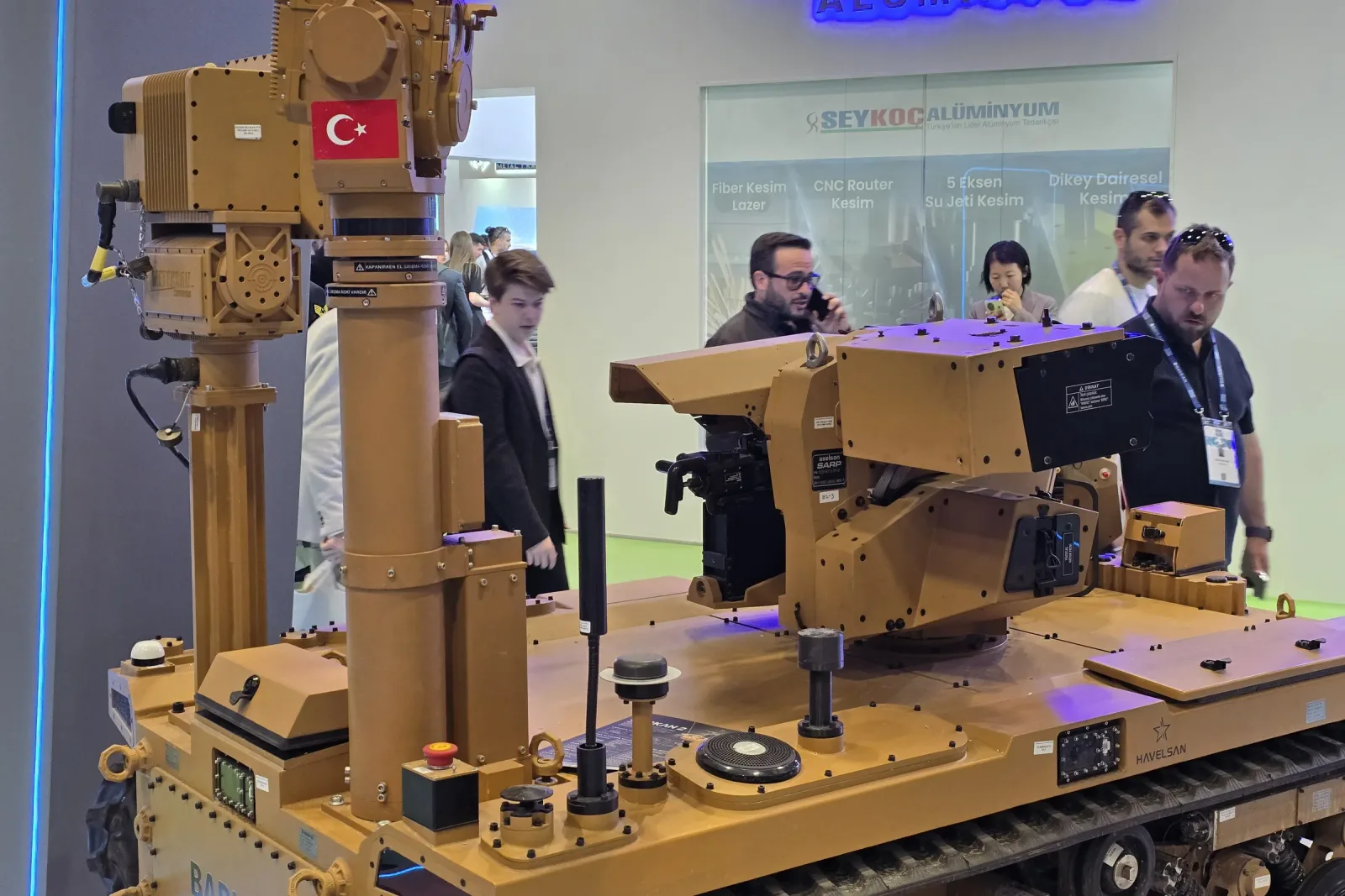 Mast tabanı ve araç güvertesi; üstte gimbal, arkada stand ziyaretçileri