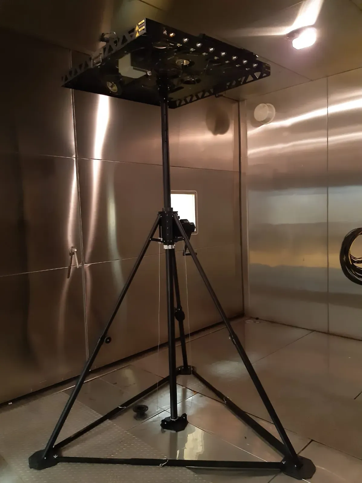 Paslanmaz çelik çevresel test kabininde açılmış, tepesinde düz maket yük plakası taşıyan tripod mast