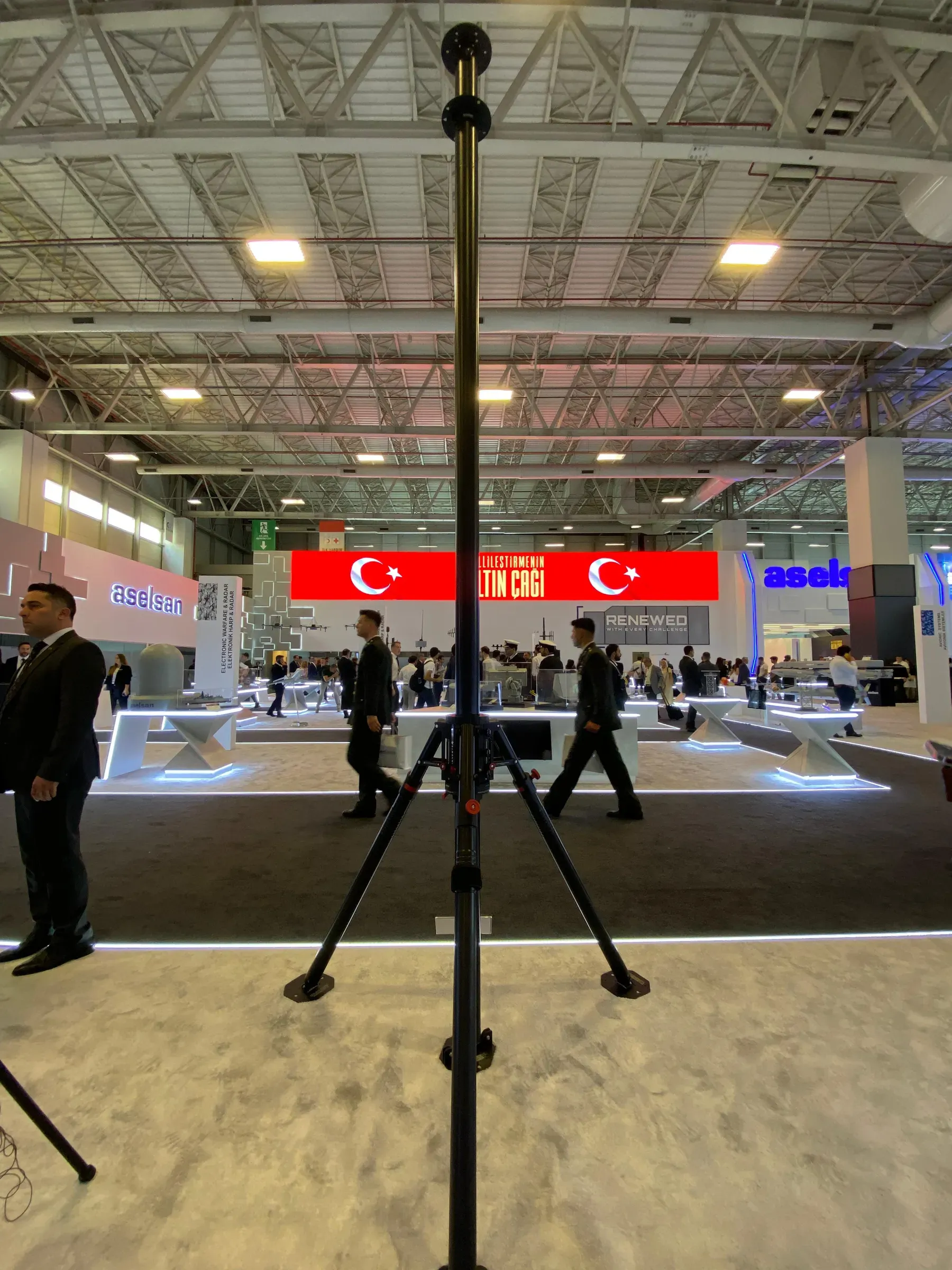 Tripodundan salon tavanına doğru açılmış uzun mast; ötesinde Türk bayrakları ve ziyaretçiler