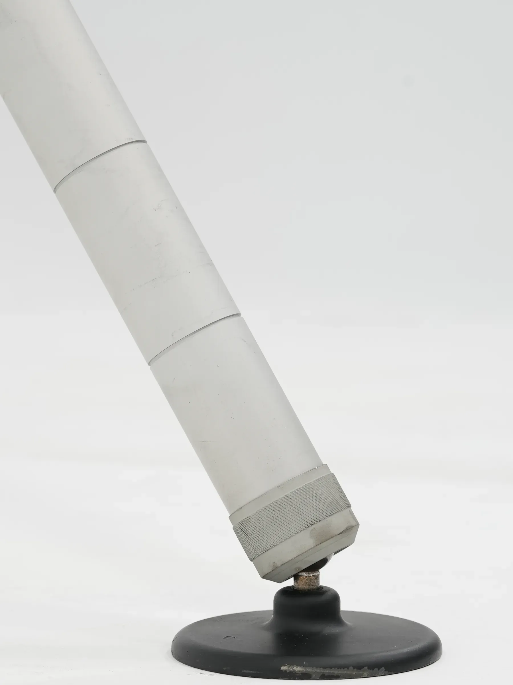 Yuvarlak siyah ayak pedine doğru açılan tek uzatılmış tripod ayağı