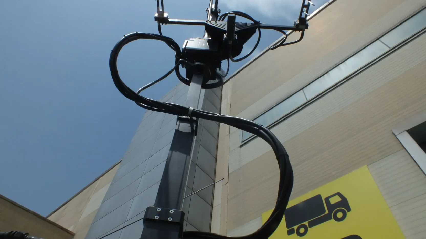 Alttan görülen mast tepesindeki anten takımı; servis kablosu geniş bir kavis çizerek mast boyunca aşağı iniyor